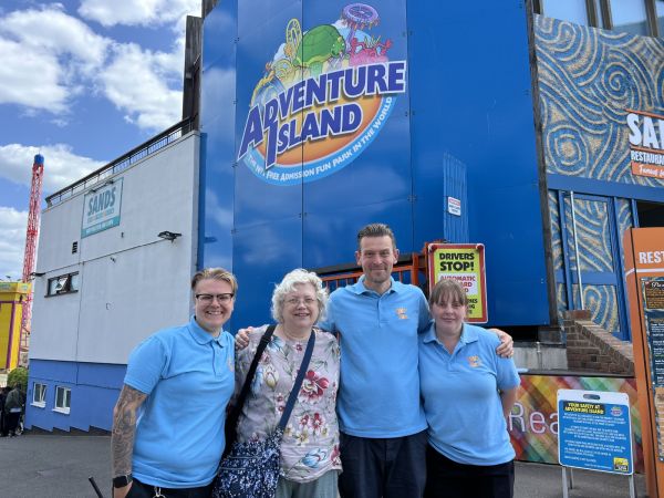 A photograph of Stella with three of the catering team (wearing their light blue uniform polo shirts), outside the Sands Restaurant at Adventure Island.